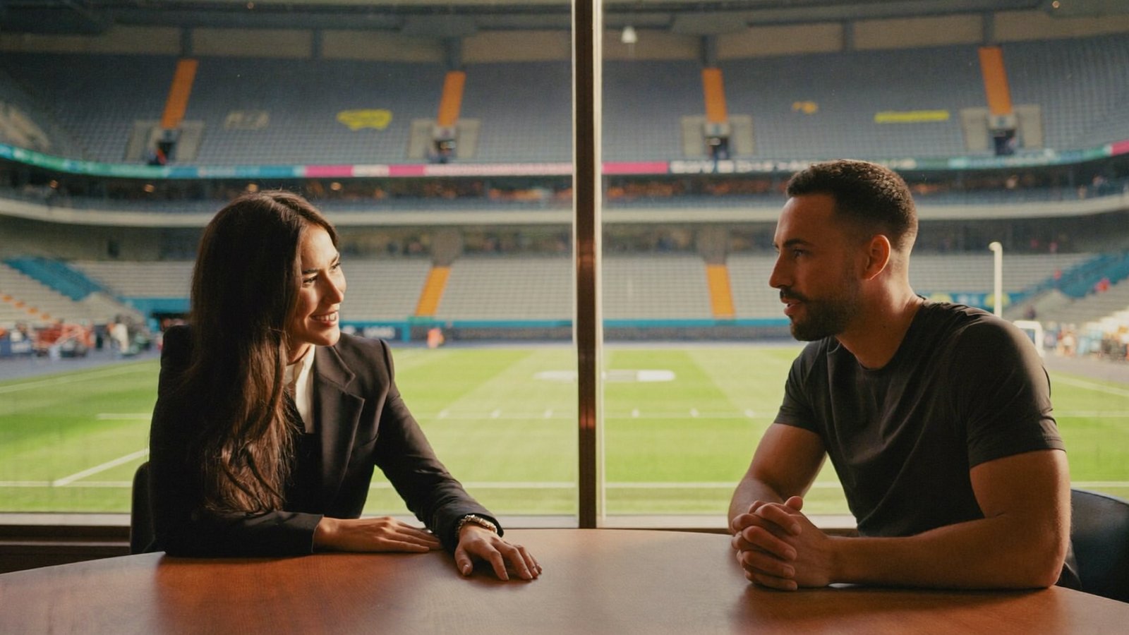Brand manager and athlete in conversation at the same table, stadium in the background